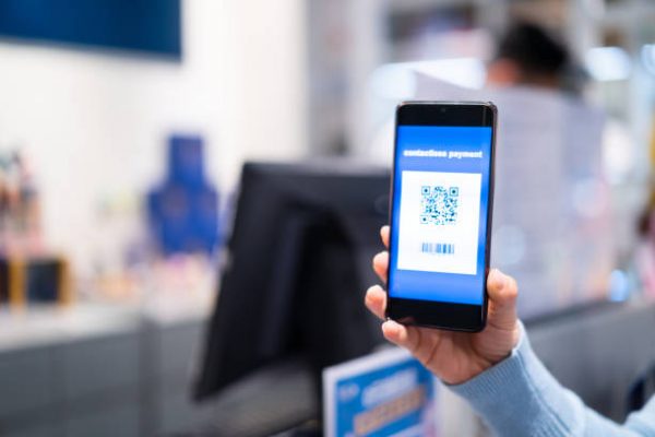 woman shows QR code in her mobile phone while she checks out woman shows QR code in her mobile phone while she checks out